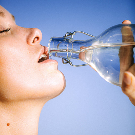 close up of a woman drinking from a bottle of water during a sunny day